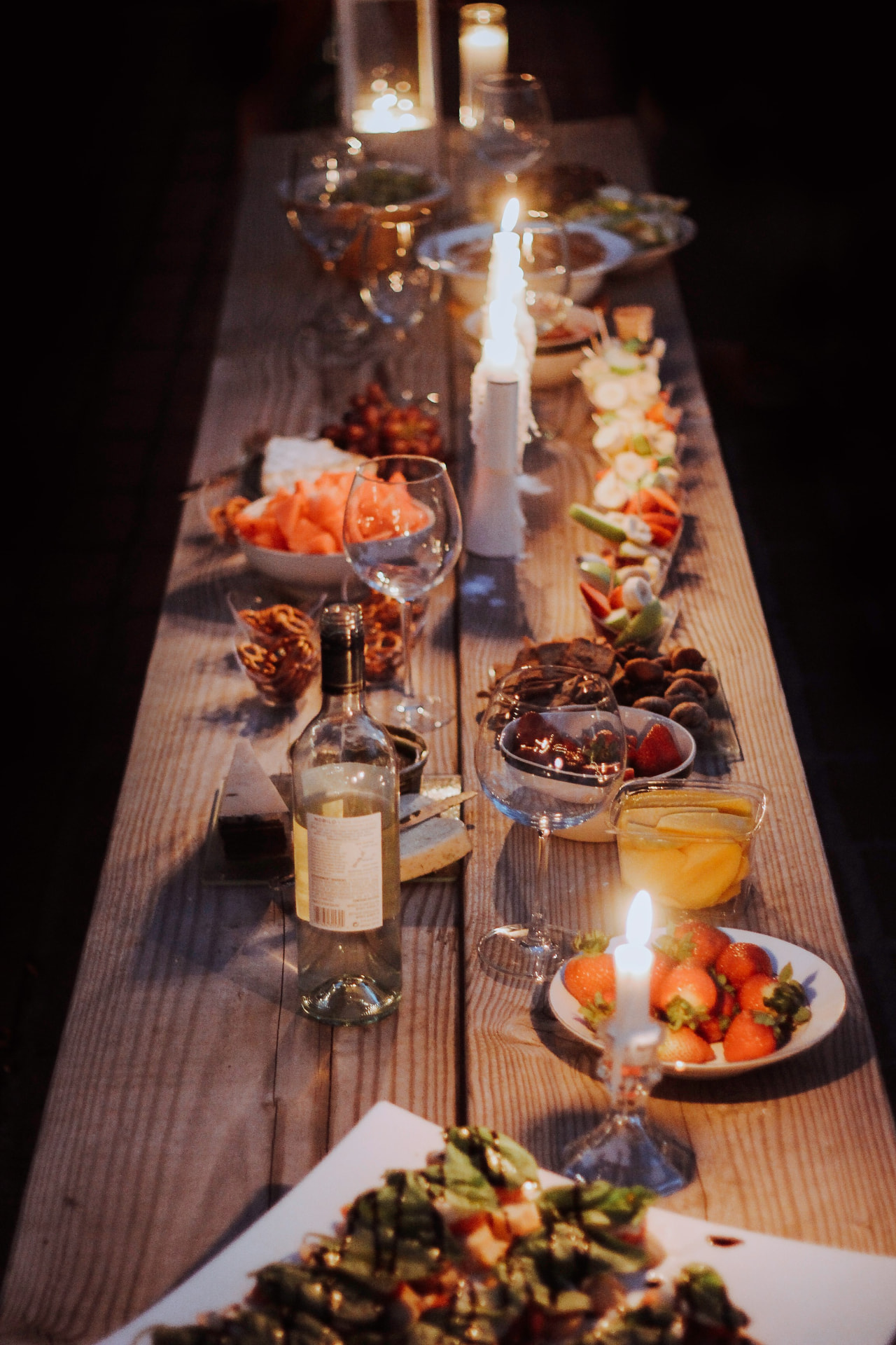 A candle-lit table set with shared plates and wine for a private dinner.